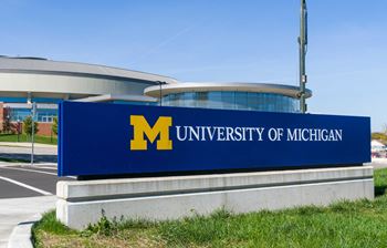 A large blue sign with a gold letter m on it that says university of michigan
